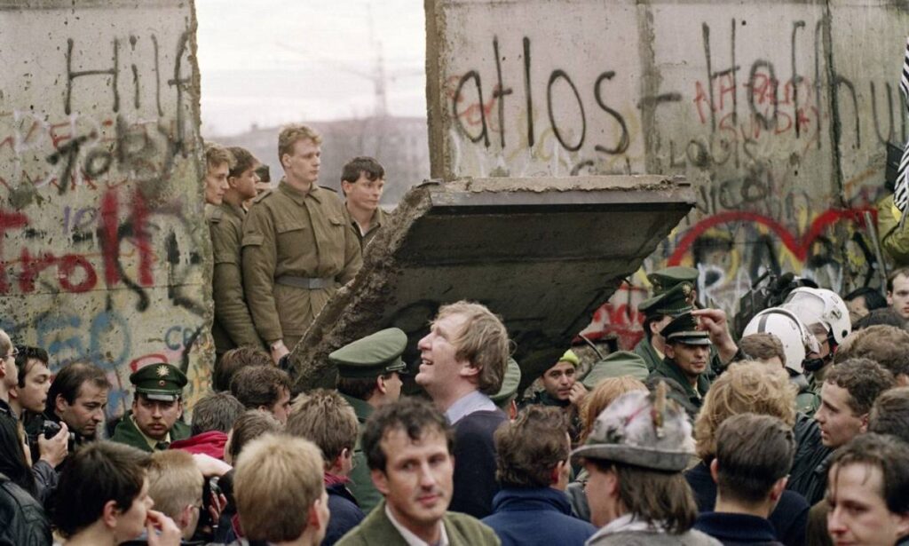 Imagem histórica da queda do muro de Berlim em 1989 em referência ao muro entre negócio e desenvolvimento que deve cair também.